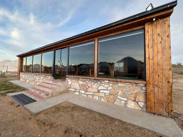 The stone and timber dining building at dusk, its windows lit