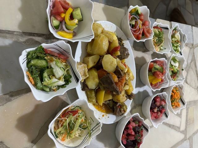 A spread of Uzbek salads and a meat and potato main course laid out for dinner