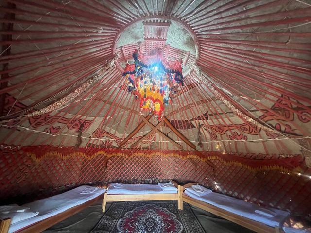 A yurt lit for the evening, beds arranged around a central carpet