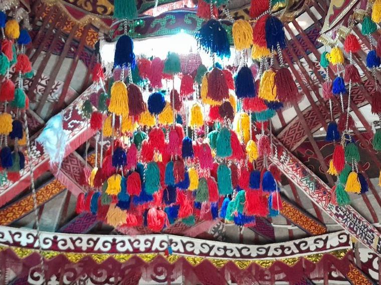 The decorated crown of a yurt, hung with coloured tassels